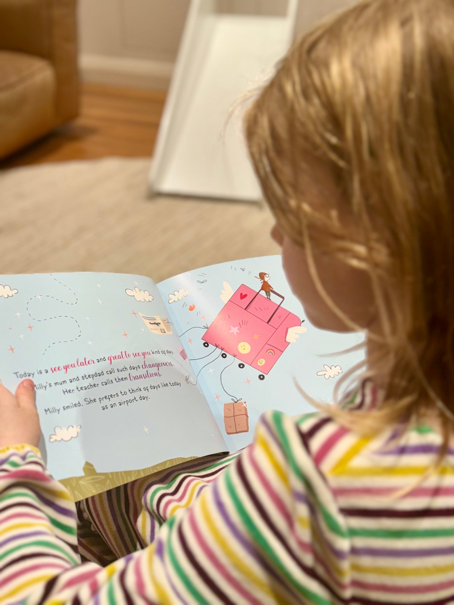 Child reading Milly's Parent Airport with colourful illustrations of a suitcase and airplane.
